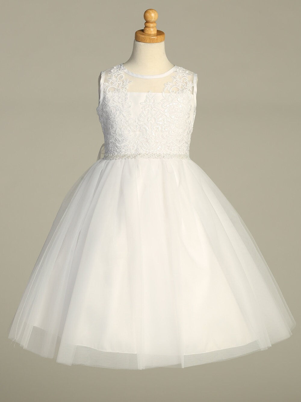 A side view of the First Communion Dress showing the corded embroidered tulle with sequins, and the elegant silhouette of the tea-length dress.