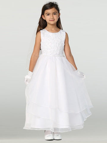 A girl wearing a stunning white First Communion Dress with a tulle bodice and organza skirt, adorned with beaded embroidered applique.