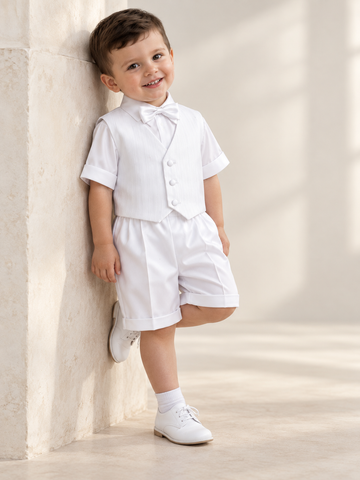 Toddler boy wearing the white 8460 baptism outfit with ribbed vest, bow tie, short-sleeve shirt and cuffed satin shorts.