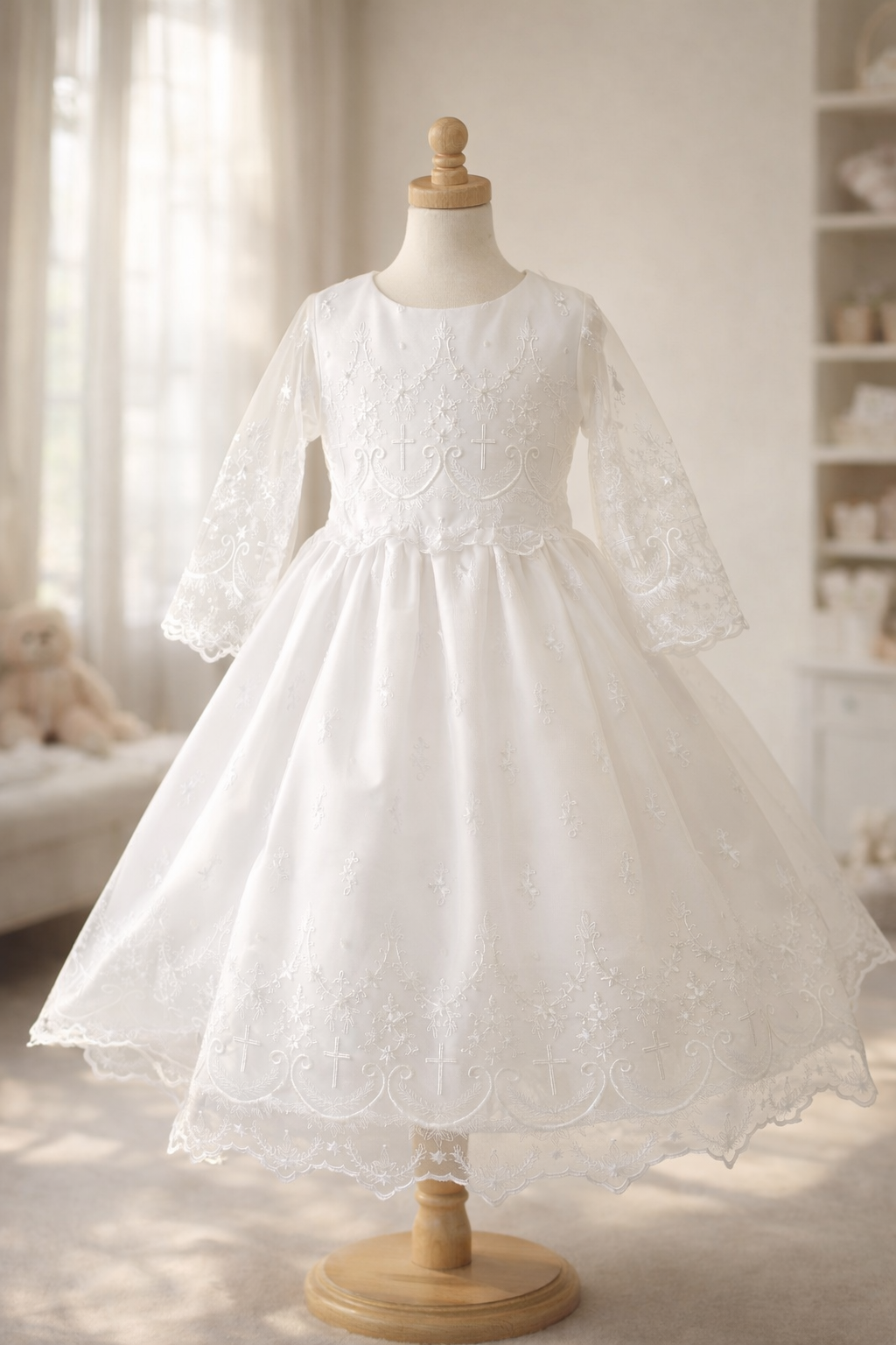 Elegant white lace dress for first communion, featuring long sleeves, floral embroidery, and a full layered skirt on a mannequin in a softly lit room.