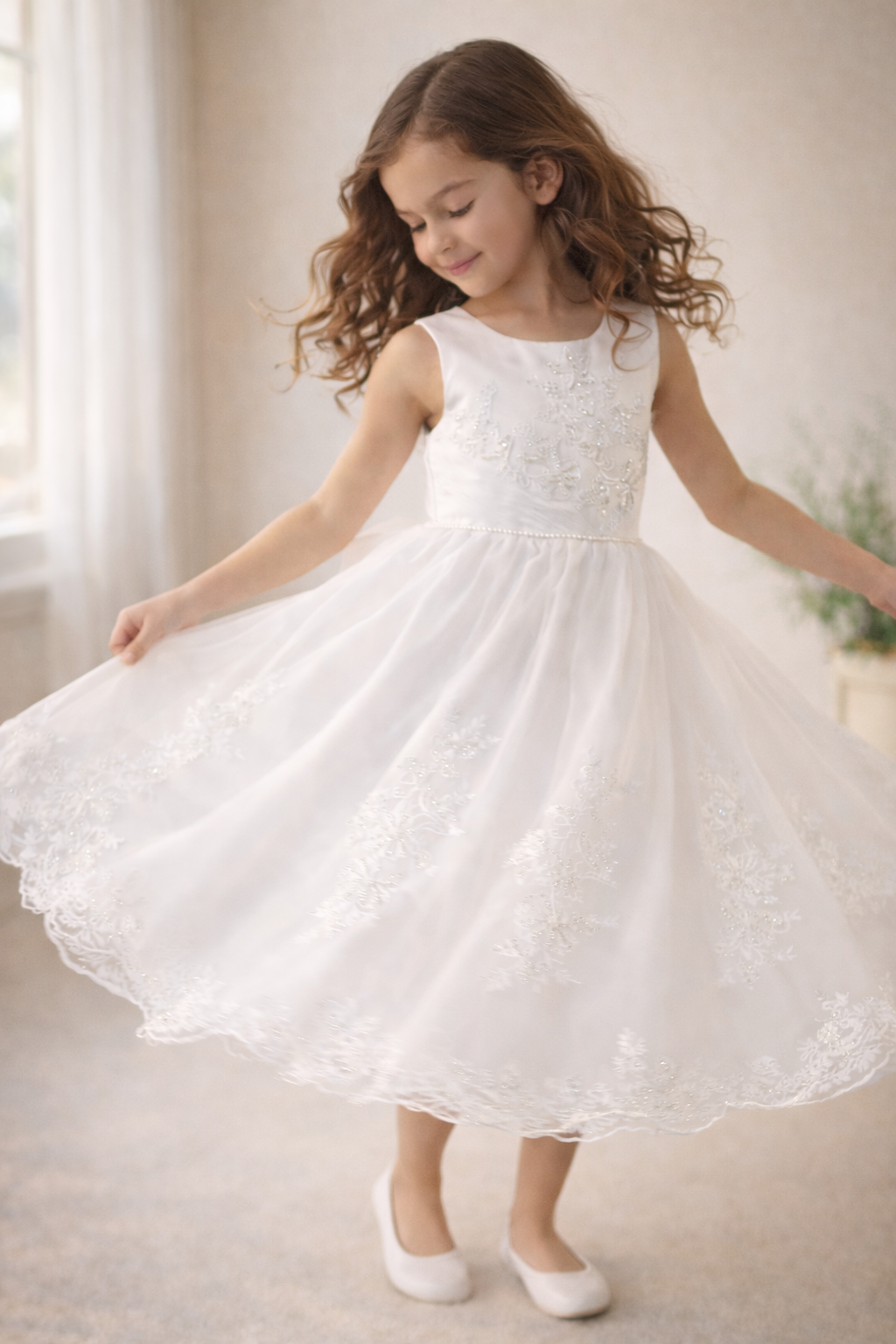 Young girl in a white communion dress standing indoors with a neutral background