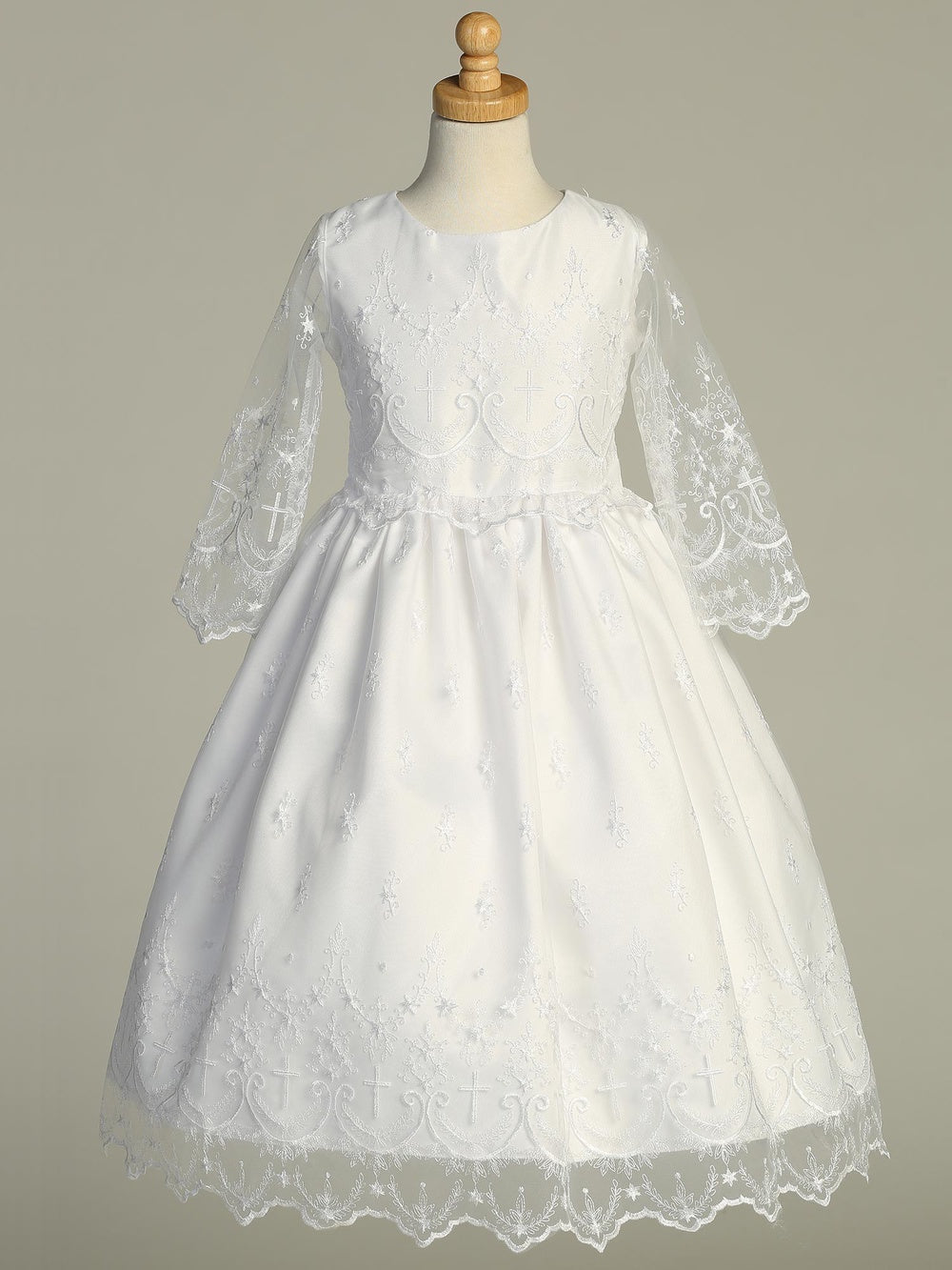 Girls White First Communion Dress displayed on mannequin, showcasing corded embroidered tulle with cross designs and scalloped hem. Perfect for special occasions.