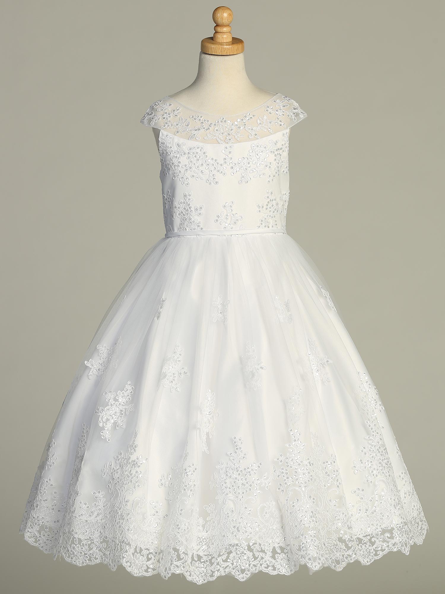 Girls White First Communion Dress displayed on mannequin, featuring embroidered tulle overlay, sequins, and scalloped neckline.