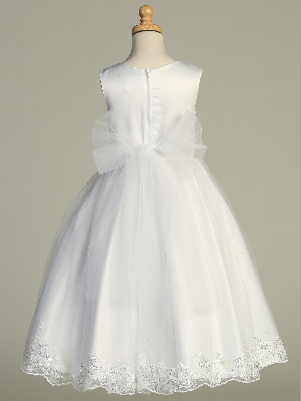 Back view of girls white communion dress featuring satin bodice, tulle skirt, and large organza bow with embroidered hem.