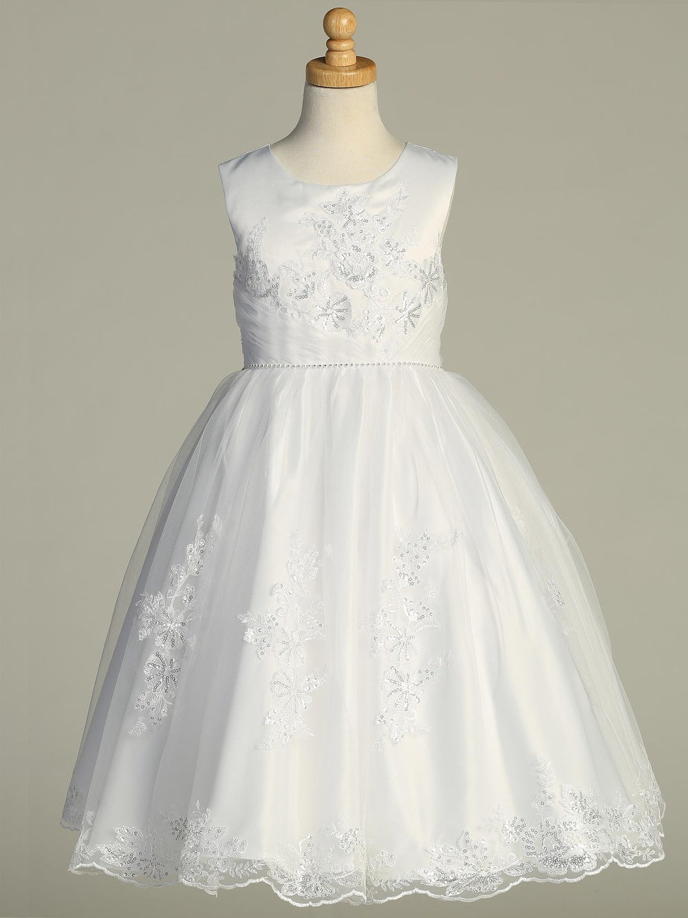 Girls white satin First Communion dress on mannequin with floral embroidered tulle overlay and rhinestone waist detail.