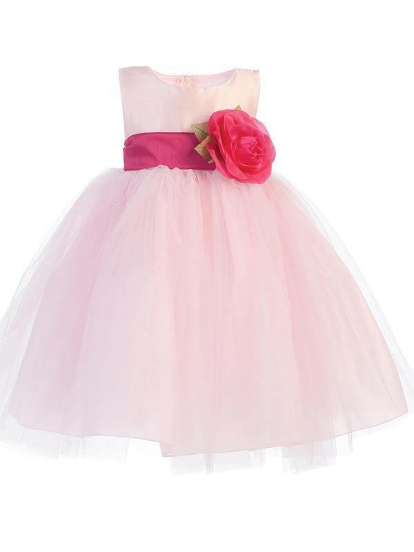 Pink flower girl dress with full tulle skirt and fuchsia sash featuring a detachable rose flower, perfect for weddings by Malcolm Royce.
