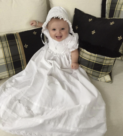 Girls White Baptism Gown Marie worn by baby, featuring smocked bodice and lace trim. Perfect for christening ceremonies with timeless elegance.