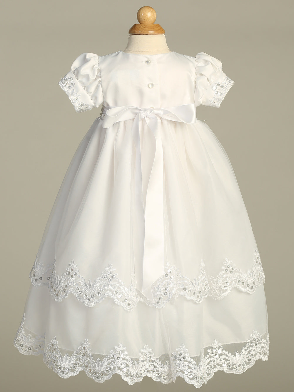 Girls White Christening Gown Naomi featuring satin bodice, puff sleeves, bow detail, and scalloped tulle hem. Elegant baptism gown with free shipping.