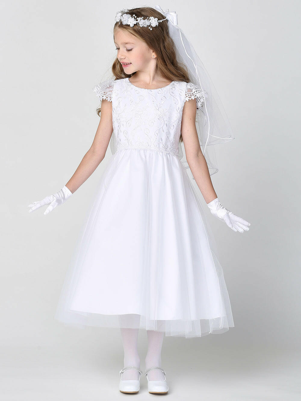 Girls white First Communion dress by Malcolm Royce featuring embroidered tulle bodice and skirt, styled with gloves and veil for ceremonial wear.