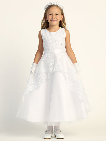 A girl wearing a stunning First Communion Dress with white embroidered tulle and sequins.