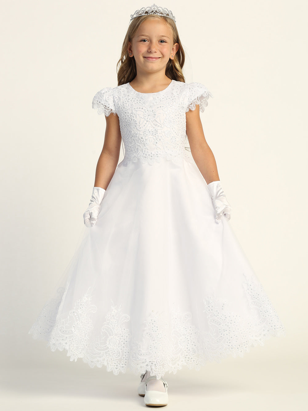 A girl wearing an elegant white First Communion Dress with embroidered tulle and sequins.