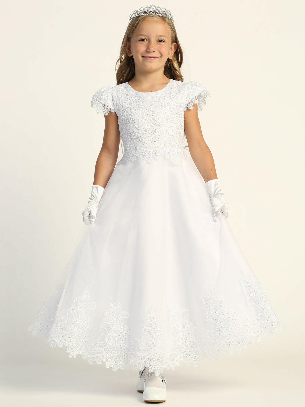 A girl wearing an elegant white First Communion Dress with embroidered tulle and sequins.