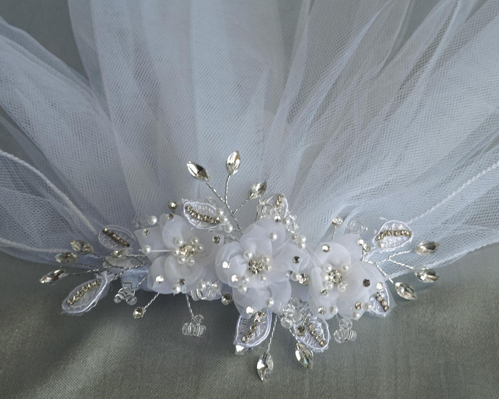 Close-up of 24" Communion veil headpiece adorned with organza flowers, pearls, rhinestones, and crystal accents for a dazzling finish.