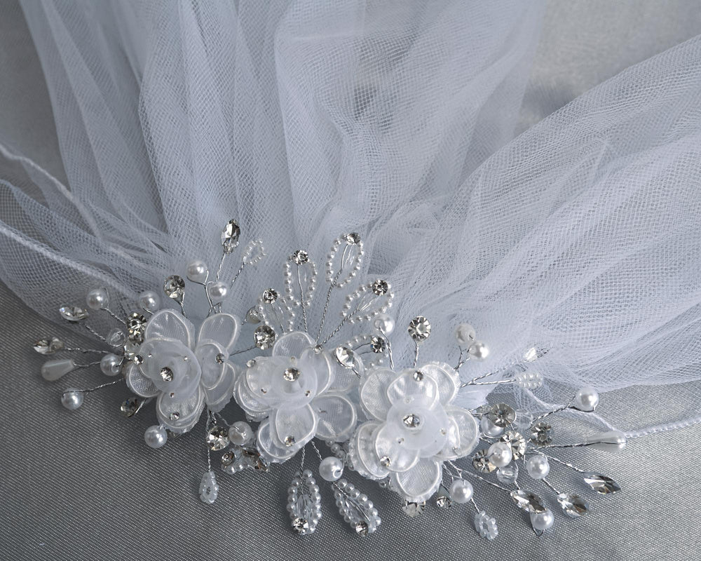 Close-up of 24" Communion Veil's floral comb with organza corded flowers, rhinestones, and pearl sprays for a delicate ceremonial look.