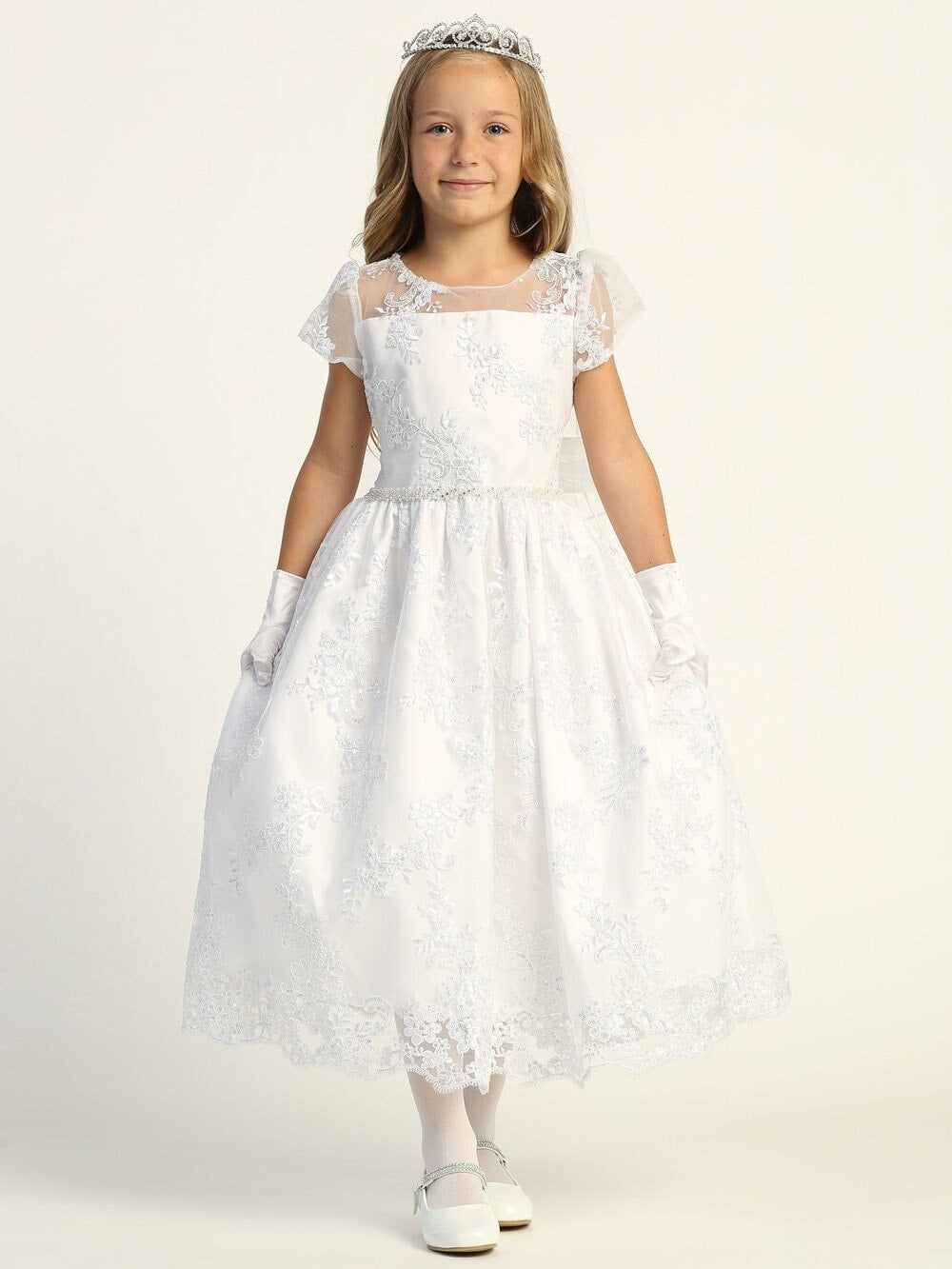 A girl wearing a stunning white First Communion Dress with embroidered tulle and sequins, featuring a soft acetate lining.