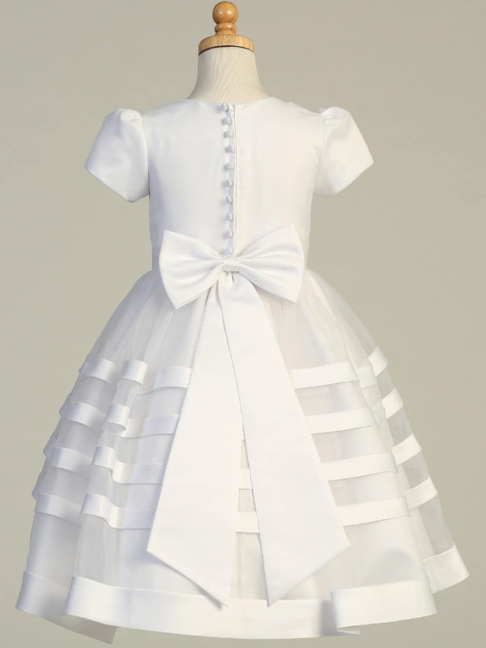 Back view of Girls' First Communion Dress showing satin bow, button-up closure, and layered organza skirt for a classic ceremonial look.