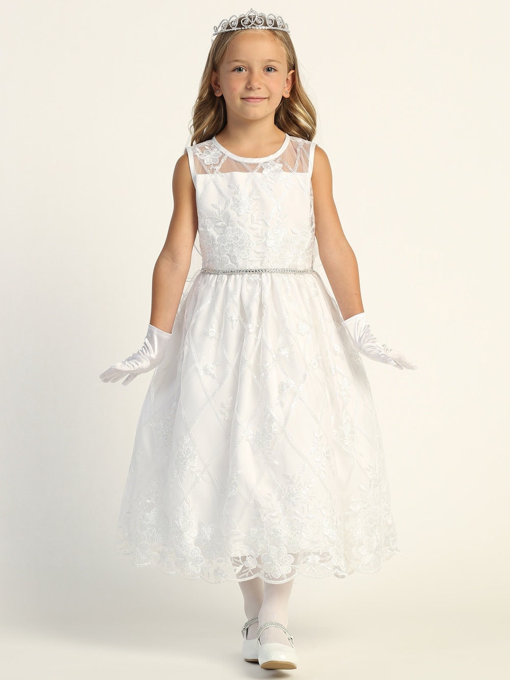 A girl wearing a sparkling white First Communion Dress adorned with embroidered tulle and sequins, featuring a soft acetate lining. (This is the actual image from the listing)
