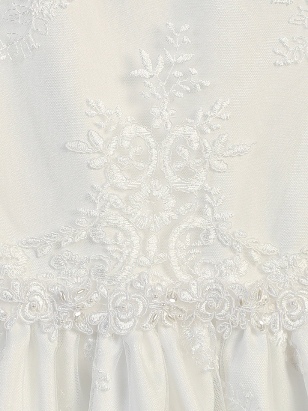 Close-up of corded embroidery lace detail on the white First Communion dress, showcasing floral patterns and fine craftsmanship.