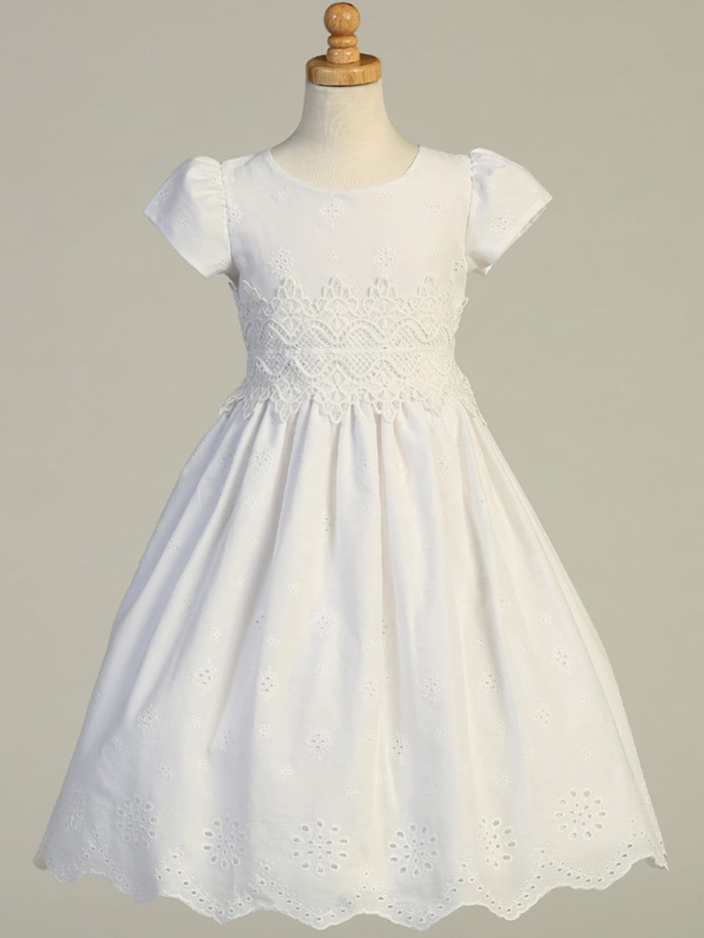 A full-length view of the First Communion Dress showing the elegant silhouette and cotton eyelet fabric.