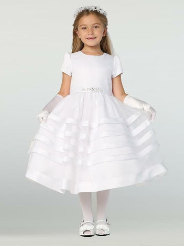 A girl wearing a beautiful white First Communion Dress with a satin bodice and organza skirt.